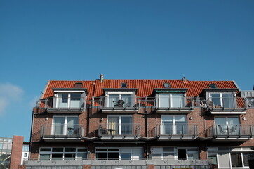 Mehrfamilienhaus mit Klinkerfassade, Balkons, Dachgauben und Ferienwohnungen vor blauen Himmel an...
