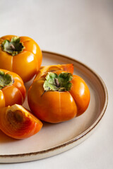 Fresh bright orange autumn persimmon on white background