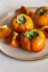 Fresh bright orange autumn persimmon on white background