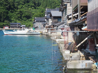 Fototapeta na wymiar Spectacular view of Sea of Japan coast olf fishing village of Ine in Kyoto prefecture in Japan with old fishing houses, blue sky and turquoise waters of a bay on a sunny day