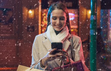 Fototapeta na wymiar Happy woman doing Christmas shopping and using her smartphone