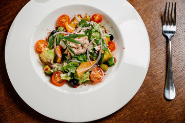 Caesar salad with croutons, quail eggs, cherry tomatoes and grilled chicken in wooden table