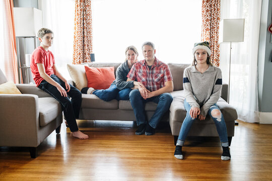 Editorial Portrait Of Family With Teenagers On Sofa At Living Room At Home