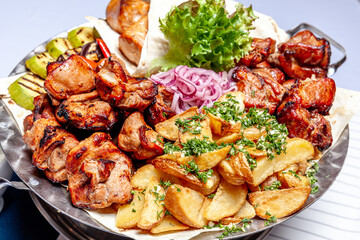 Mixed grill meat fried vegetables and grilled salmon fish fillets decoration in warm dish. Assorted delicious grilled kebab served with herbs on platter. Restaurant menu barbecue plate Bbq party meal