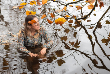 Lady wearing a dress, inside of the water in a autumn day