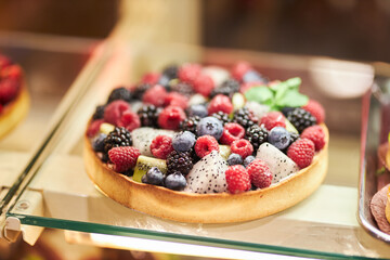 Cake with fresh berries on the glass counter in the bakery. cakes with fresh berries. tartlets with yogurt, raspberries and blackberries, strawberries and blueberries. 