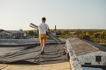 Worker applies pvc synthetic membrane roller on roof very carefully.