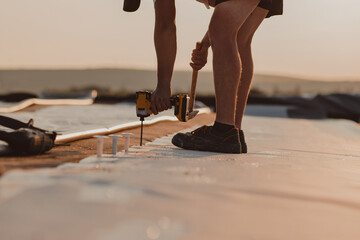 The worker uses a drill to tighten the screws to the roof membrane fixing.
