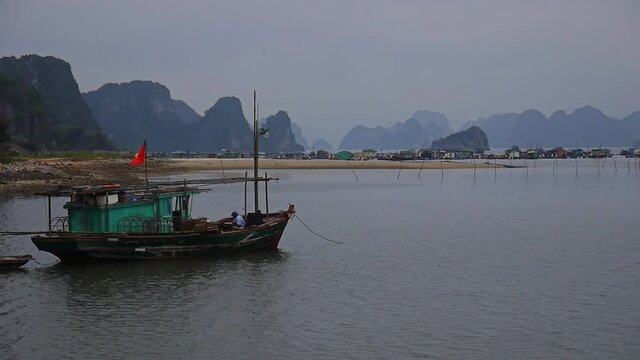 An old fishing boat in Halong Bay in Vietnam. The red Vietnamese flag flutters on board.