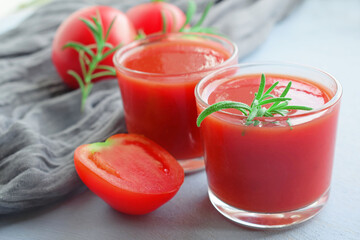 Tomato juice in a glass glass and fresh tomato on a wooden background.