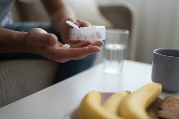 Cropped man taking vitamins at home