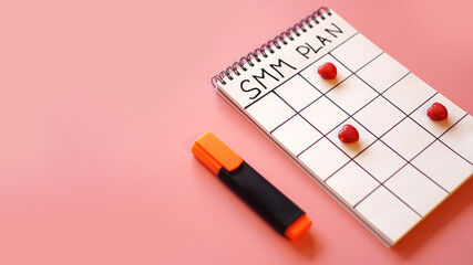 Social media marketing concept - SMM plan in a notebook on a pink background with candy in the form of hearts