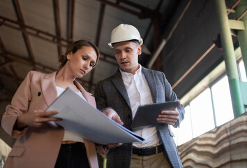 Contemporary engineers examining draft in warehouse building