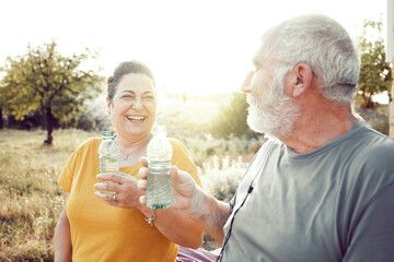 An older couple laughs while resting to drink water
