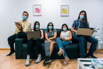 Group of young people wearing masks during a break in a Coworking office.