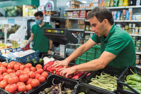 a shopkeeper placing fruit in the greengrocer's