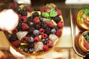 Cake with fresh berries on the glass counter in the bakery. cakes with fresh berries. tartlets with yogurt, raspberries and blackberries, strawberries and blueberries. 