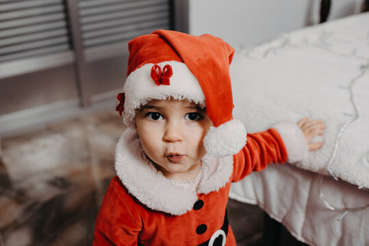 A little girl disguised as Santa Claus looking at the camera.