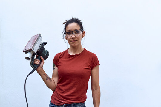 Young Woman With A Power Sander On A White Background.