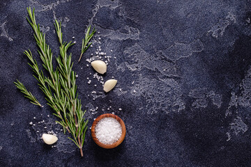 Herbs and condiments on black stone background.