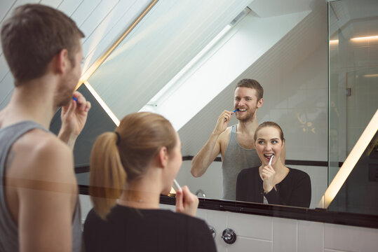Young couple brushing teeth together