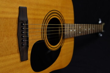 Classic wooden acoustic guitar closeup, on a black background, rock, country music concept