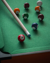A child's miniature pool table with numbered balls and a small snooker cue