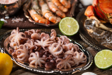 Close-up top view of assorted seafood. Cooked crab, baby octopuses and tiger shrimps served with lime and seashells on rustic wooden background. Seafood concept. Delicious meal.