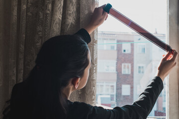 Una mujer examina una tira de película de 35 mm con negativos en blanco en una ventana