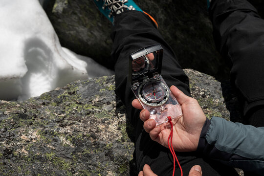 Closeup contemporary compass in women's hand in mountains with snow