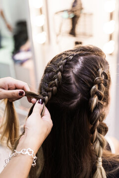 Hairdresser making braids to a young client at Hairdresser salon