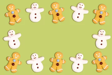Muurstickers Speelgoed Kerstkoekjes frame in de vorm van een sneeuwpop en een peperkoekman versierd met poedersuiker en fondant op een groene achtergrond