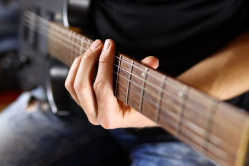 guitarist plays an electric guitar chord on a black background. Selective focus