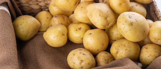 New raw potatoes in a wicker basket on a brown background close up