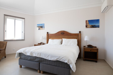 Master bedroom with wooden furniture and white bedding in a renovated holiday villa