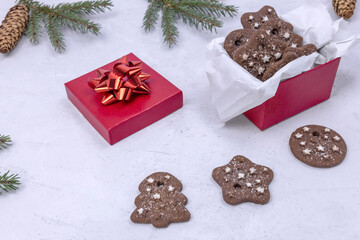 Christmas chocolate cookies with cinnamon in a red gift box and spruce branches on a light background