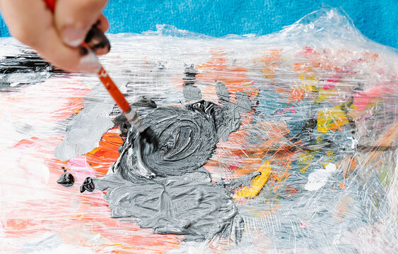 hand with a brush mixing a color painting on a painting palette. Overhead horizontal photo
