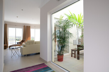 Corridor leading to modern living room bordered by an internal courtyard with plants in a mediterranean villa
