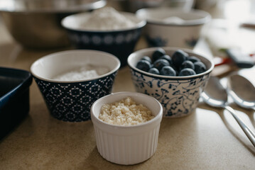 A close photo of blueberries, wheat flour, almond flour, sugar, powdered sugar which are preparing for cooking in the kitchen.