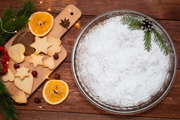 Christmas cake with decorations and winter greenery over wood's background.