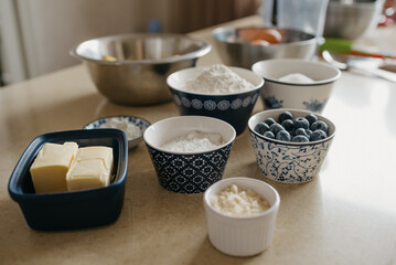 Wheat flour, almond flour, sugar, powdered sugar, blueberries, two pieces of butter, starch, eggs, lemons are preparing for the lemon meringue tart in the kitchen.