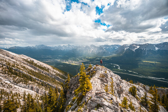 Hiker Standing on Mountain Ridge Above City of Canmore Alberta