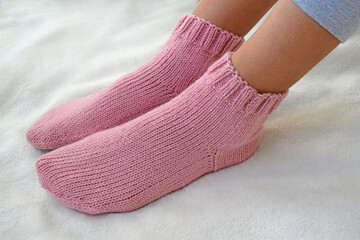 Pink wool socks tied with knitting needles.