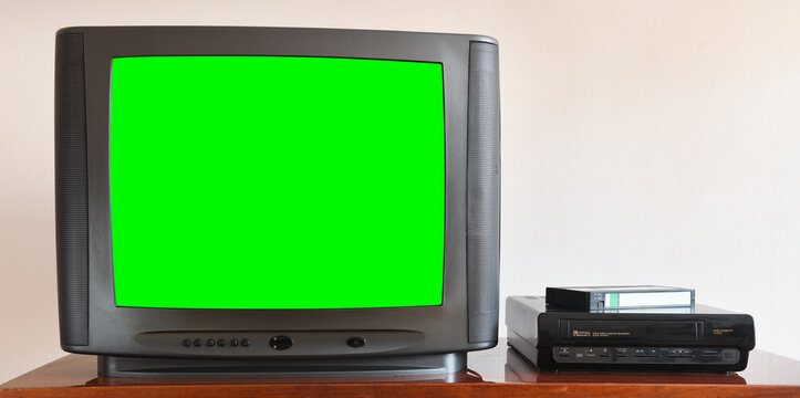 Old black vintage green screen TV from 1980s 1990s 2000s for adding new images to the screen, VCR in the background of wallpaper.