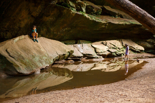Two children play quietly in a sandstone gorge by a reflective pool