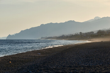 in the hour of the sunset the beach of the coast of Messina near Taormina