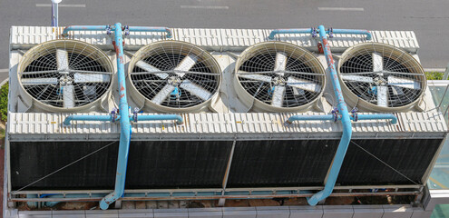 Obraz premium View from above on industrial ventilation with spinning blades or air conditioning system on roof building in Asia. Cooling system in tropical climate