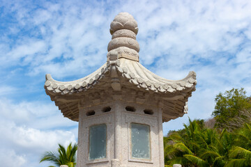 Fragment of oriental (chinese) grey stone lantern against blue sky.