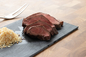 Picanha meat, Brazilian cow steak, served with farofa at a wooden table