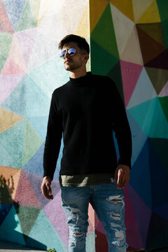 boy with sunglasses posing in front of a painted wall